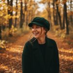 Femme portant une casquette gavroche velours vert bouteille, portrait lifestyle forêt automnale