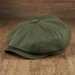 Casquette gavroche vert militaire posée sur surface en bois, photo studio produit